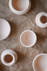 dishes made of white clay without glaze after firing on a brown background close-up. pottery top view