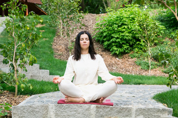 Young woman sitting meditates in the fresh air in a nature park.