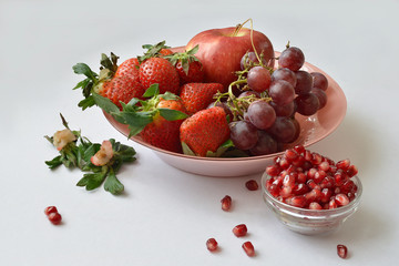 Grapes, strawberries, pomegranate seeds on a plate.