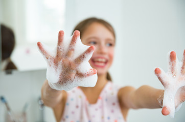 Little girl washing hands with water and soap in bathroom. Hands hygiene and virus infections...