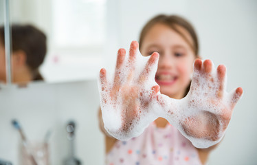 Little girl washing hands with water and soap in bathroom. Hands hygiene and virus infections...