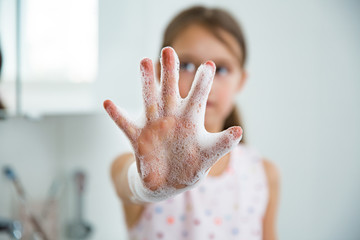 Little girl washing hands with water and soap in bathroom. Hands hygiene and virus infections...