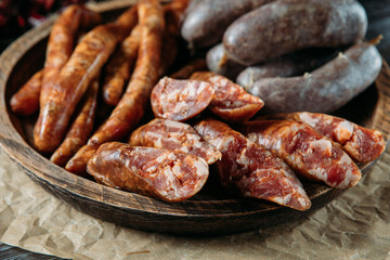 Close-up photo of traditional three kinds of meat sausages in rustic wood bowl on natural black wood table. Perfect man meal.