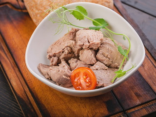 Close-up of cod liver with microgreens and cherry tomatoes, chabbat in a white bowl on a wooden cutting board. Sea food