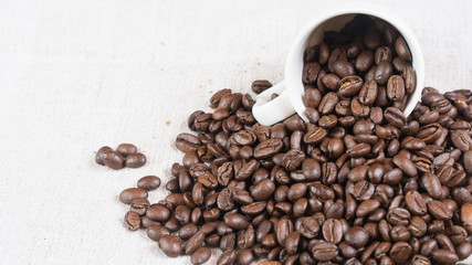  coffee beans spill out of a cup.