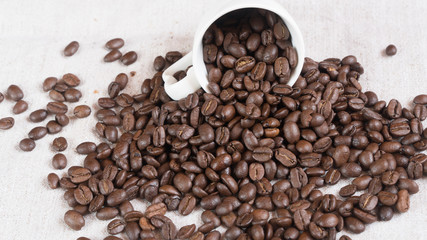  coffee beans spill out of a cup.