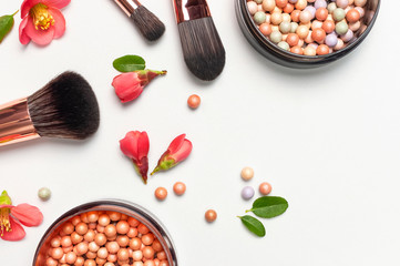 Professional makeup brushes powder blush balls with pink spring flowers on light background flat lay top view copy space. Beauty product, makeup, women's accessory, fashion. Cosmetic makeup Set