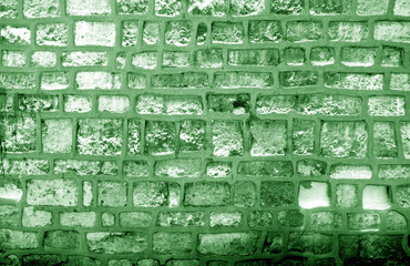 Wall made of old stones in green tone.