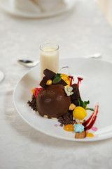 Elegant chocolate ice cream and fruit decorated with black chocolate, sauces, macaron and cream. Gourmet dessert