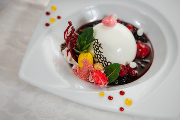 White iced cake with fruits and chocolate. Beautiful dessert in a restaurant.