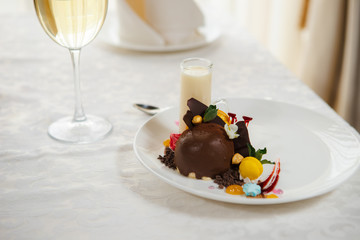 Elegant chocolate ice cream and fruit decorated with black chocolate, sauces, macaron and cream. Gourmet dessert