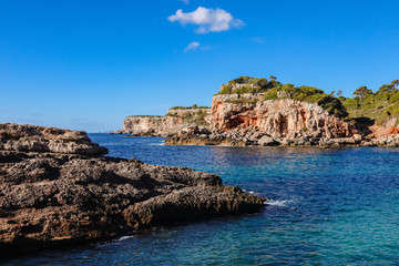 Marine seascape with rocks in the wild nature. Calm sea water. White clouds on a blue sky over summer sea on an island. Tropical sea relax on vacation.