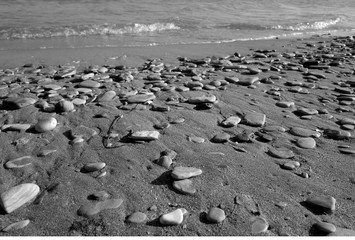 Fototapeta na wymiar Small stones sand and sea wave in black and white.