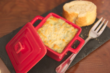 Small casserole with a gratin, a fork and a piece of bread