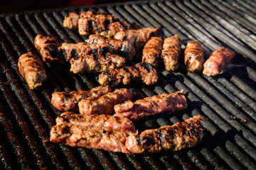 Grilled meat rolls called Mici or Mititei, traditional fresh Romanian barbeque grill food cooked on the barbeque at a street food market