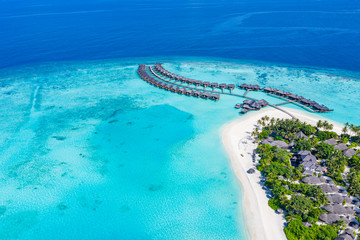 The drone photo with a wooden water villas seen from above and an amazing blue lagoon crystal clear water close to tropical lagoon. Amazing summer travel and vacation background. Dreamy beach scenery