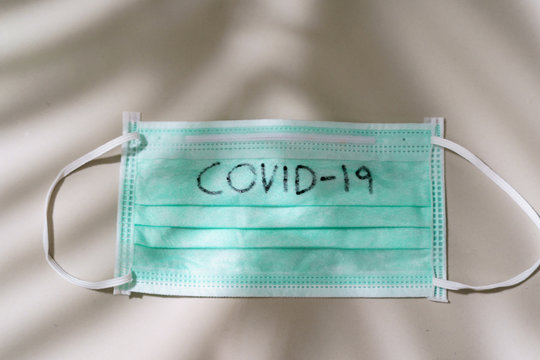Surgical mask with COVID-19 text written on Mask.