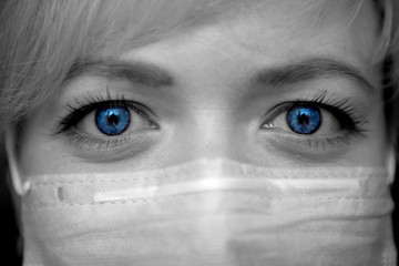 woman face with big blue eyes in a medical mask close-up