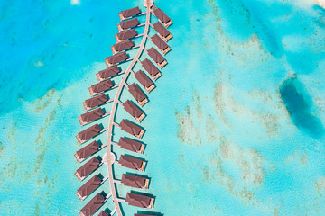 The drone photo with a wooden water villas seen from above and an amazing blue lagoon crystal clear water close to tropical lagoon. Amazing summer travel and vacation background. Dreamy beach scenery