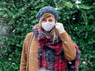 Winter portrait of woman on street wearing protective face mask and gloves.