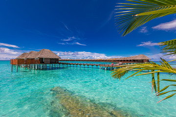 Obraz premium Maldives island, luxury water bungalows villas resort and wooden pier. Beautiful sky and clouds and beach background for summer vacation holiday and travel concept