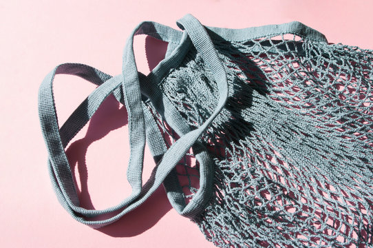 Blue cotton string knitted bag on pink background. Top view, flat lay. Zero waste, eco friendly shopping. Empty hahd made bag.