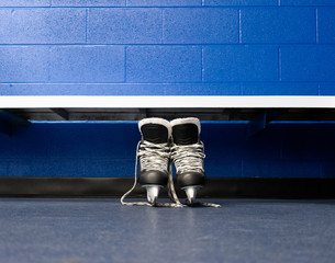Hockey skates over floor in locker room with blue background and copy space