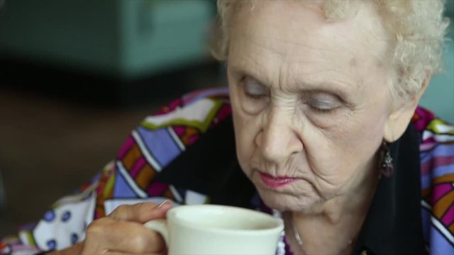 Elderly Woman Sips Beverage