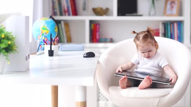 cute little baby girl watching educational video on graphic tablet at home