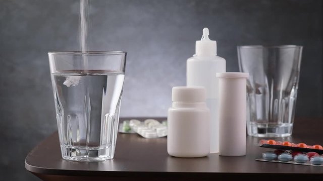 Medicament for arvi or flu. Powder medicine pour out in glass with water on background medical tablet