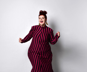 Obese redhead lady in striped dress and earrings. She reaching her hand to you while posing...