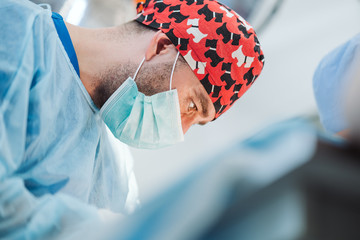Work-focused doctor. Surgeon during surgery. A professional surgical lamp in the background....
