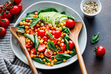 Fresh healthy salad with chickpea, avocado, cherry tomatoes and spinach.