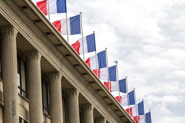 Closeup of a row of french flags waving on a roof top