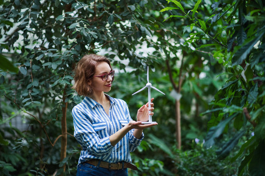 Young woman standing in botanical garden, holding windmill model.