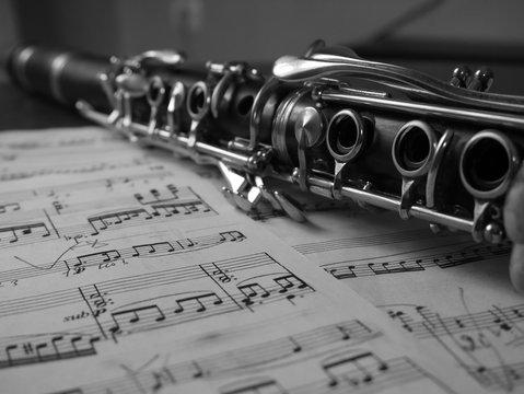 Close up of a clarinet music instrument and music notes . Black and white photo .
