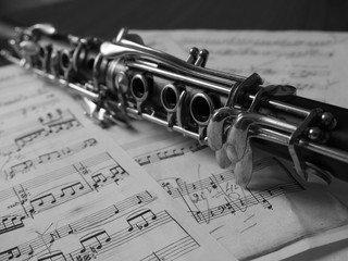 Close up of a clarinet music instrument and music notes . Black and white photo .
