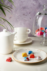 Modern chocolate candy on white plate and white teapot