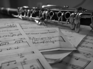 Close up of a clarinet music instrument and music notes . Black and white photo .