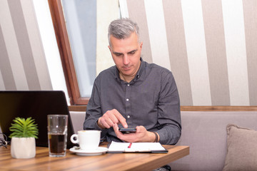 Fototapeta premium Businessman using laptop at phone in the cafe
