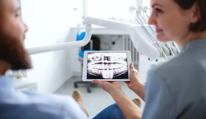 Rear view of dentist talking to man in dentist surgery, a dental check-up.