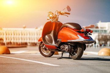Rückansicht des orangefarbenen Retro-Vintage-Motorrollers, der auf der Straße unter blauem Himmel in der europäischen Stadt steht.