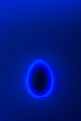 Glossy dark egg on trendy neon blue background with white backlight. Easter concept. Place for text.