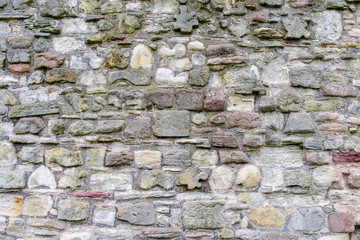 Minimalist monochrome textured natural background of many gray stones in a wall  in sunny spring garden