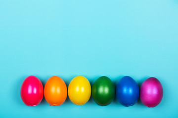 Different colorful eggs in neon trendy colors on blue pastel background. Easter concept. Flat lay style.