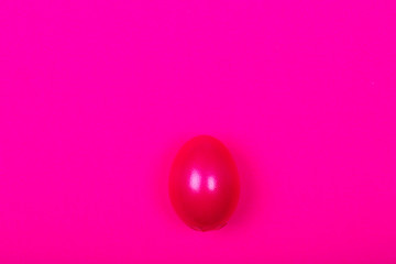 Beautiful purple egg on plastic pink neon background. Easter concept. Top view.