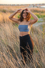curly black hair african american young woman posing smiling in field, vertical picture