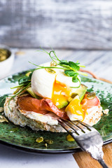Poached egg on toast, with smoked salmon, avocado, grilled tomato, and baby spinach. Microgreen. Healthy food concept. crispbread, bread crusts. Diet food concept
