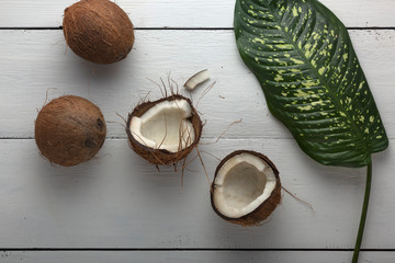 Fototapeta na wymiar Chopped coconut with green leaves on a white wooden table
