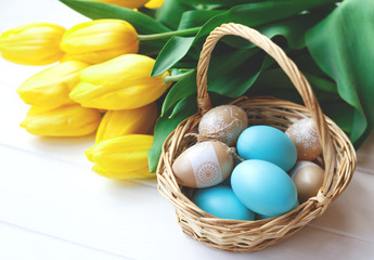 basket with vintage easter eggs and a bouquet of yellow tulips